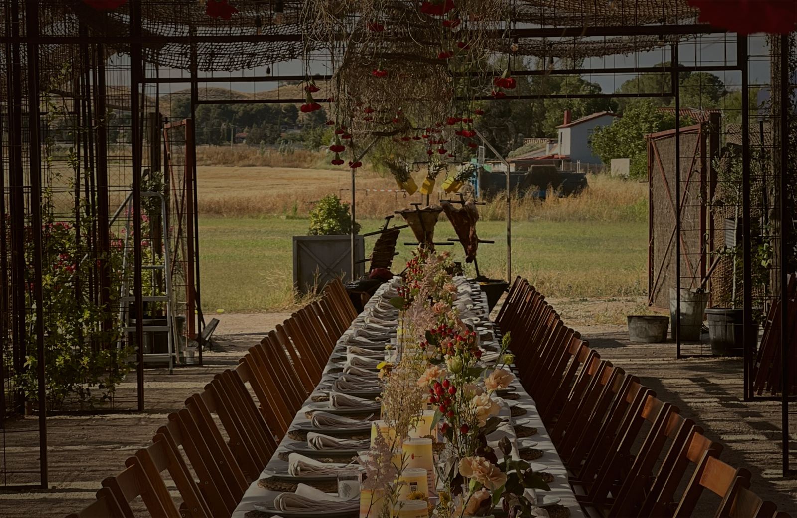 Cena de empresa en mesa larga al aire libre con asado y flores