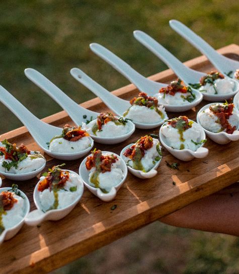 Cucharas de aperitivo gourmet servidas sobre tabla de madera en un evento familiar de El Ombú