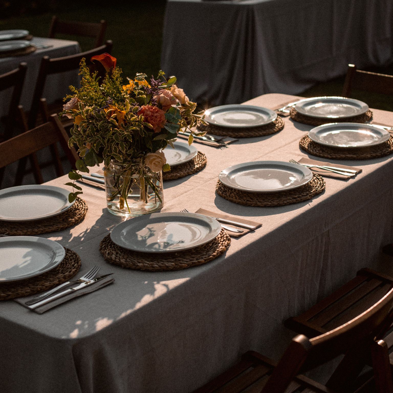 Montaje de mesa con vajilla, flores y luz cálida